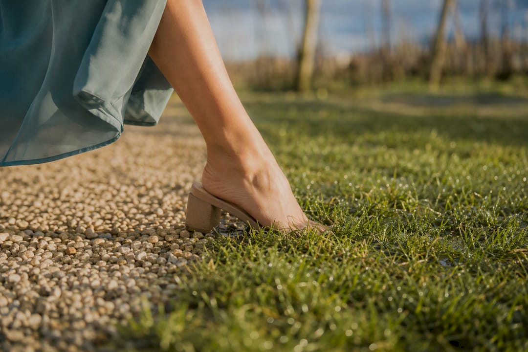 Block heel stepping onto vineyard grass