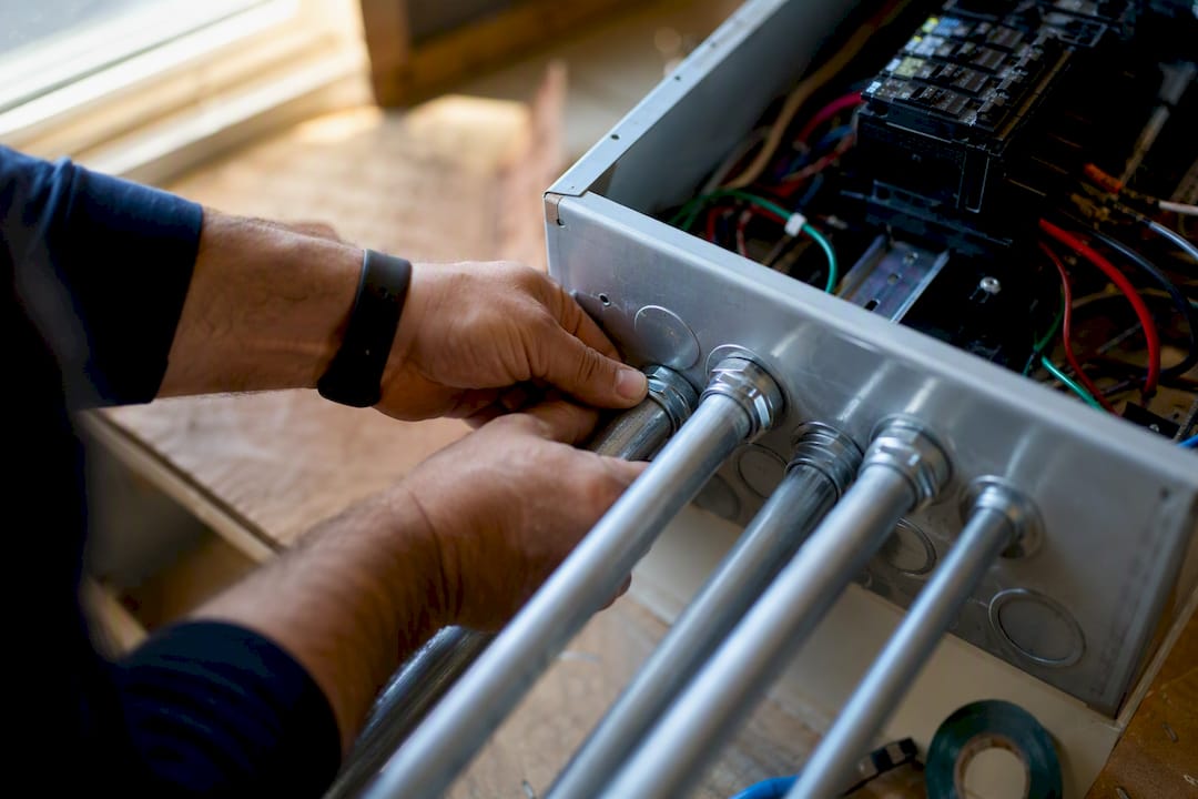 Electrician tightening conduit in panel