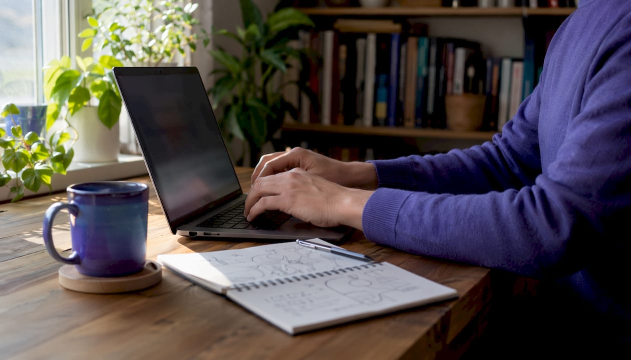 Hands typing on laptop with map nearby