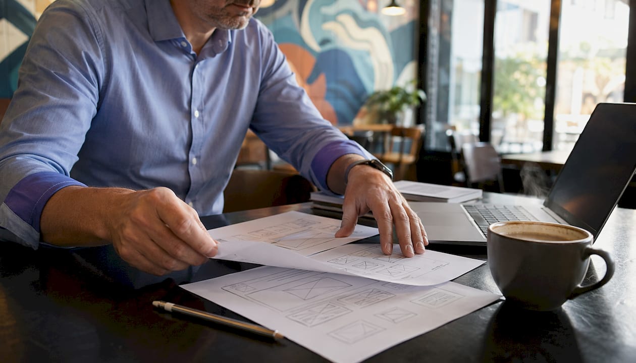 Hands arranging hero section wireframes on table