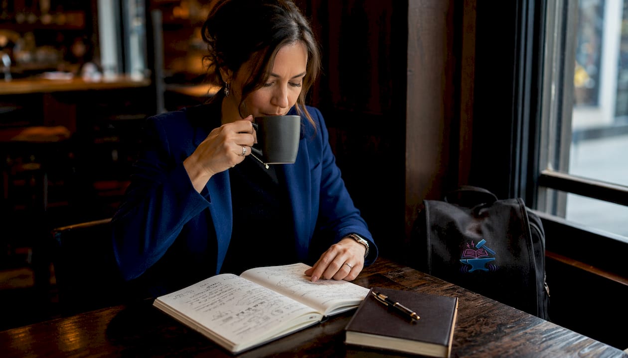 Hands near notebook and tea illustrating focused audio comprehension