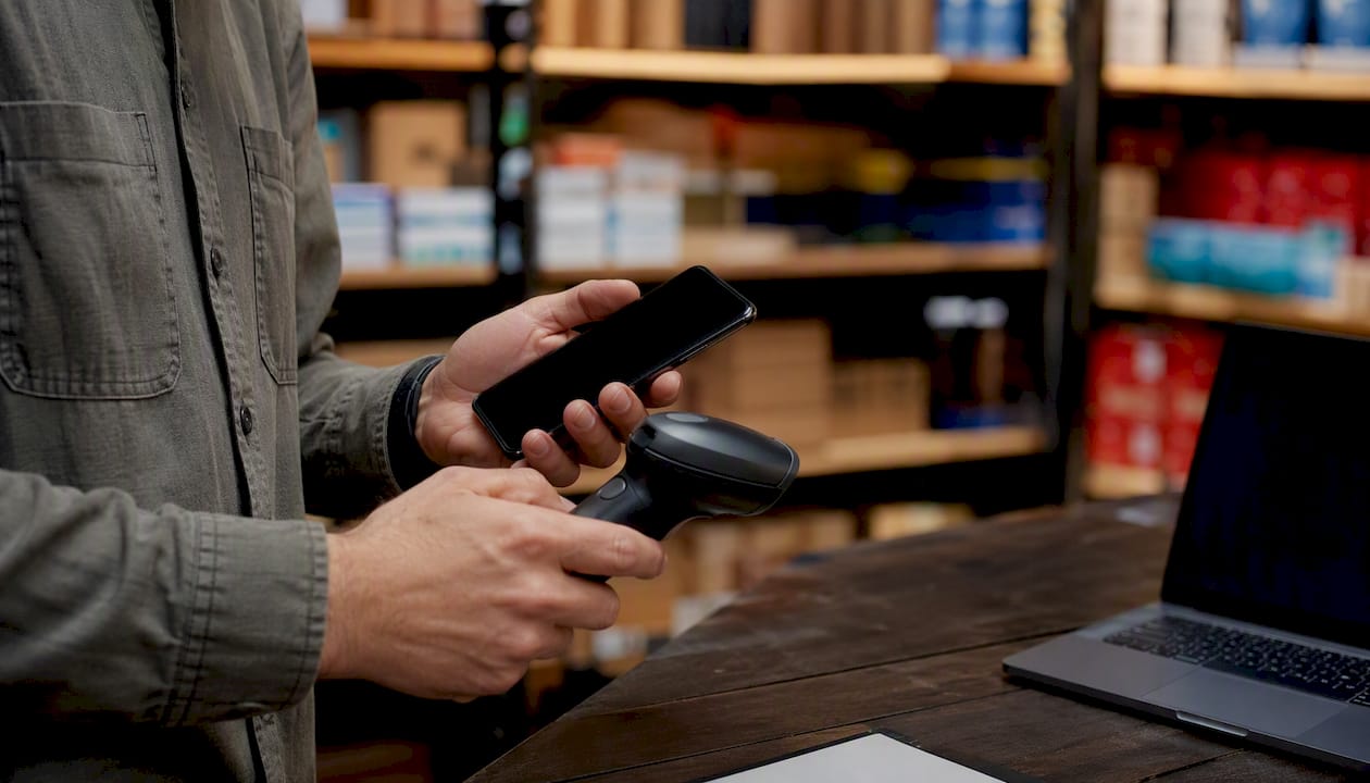 Hands installing WiFi barcode scanner in retail aisle