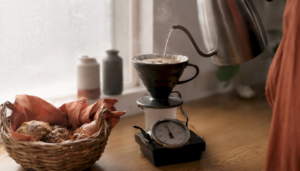 Close-up of kettle pouring water over light roast coffee grounds