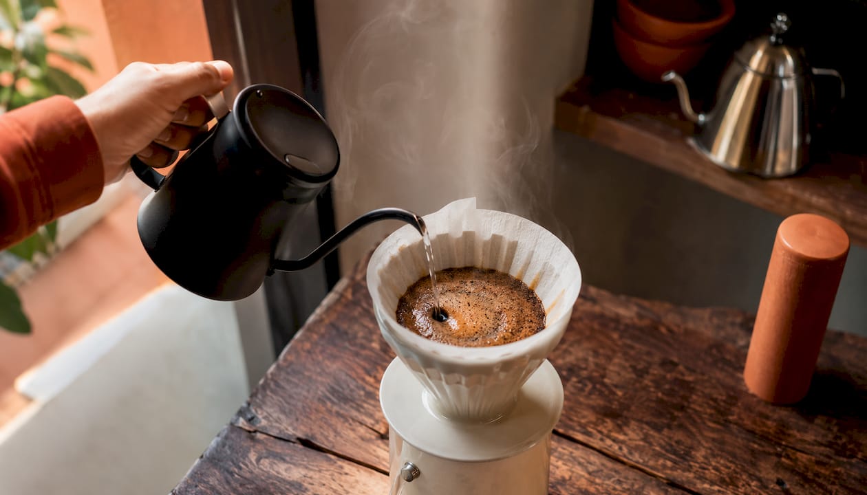 Barista pouring water over ultra light roast grounds