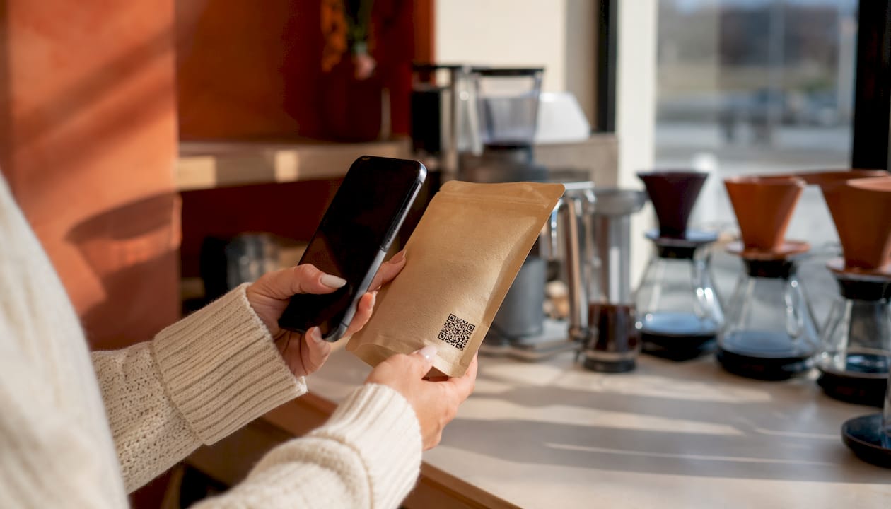 Hands scanning QR code on coffee bag in warehouse