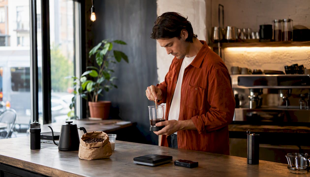 Person stirring coarse grounds in glass French press