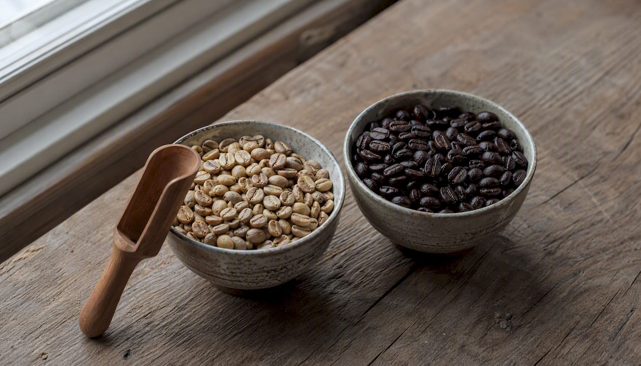 Light and dark roasted coffee beans in bowls