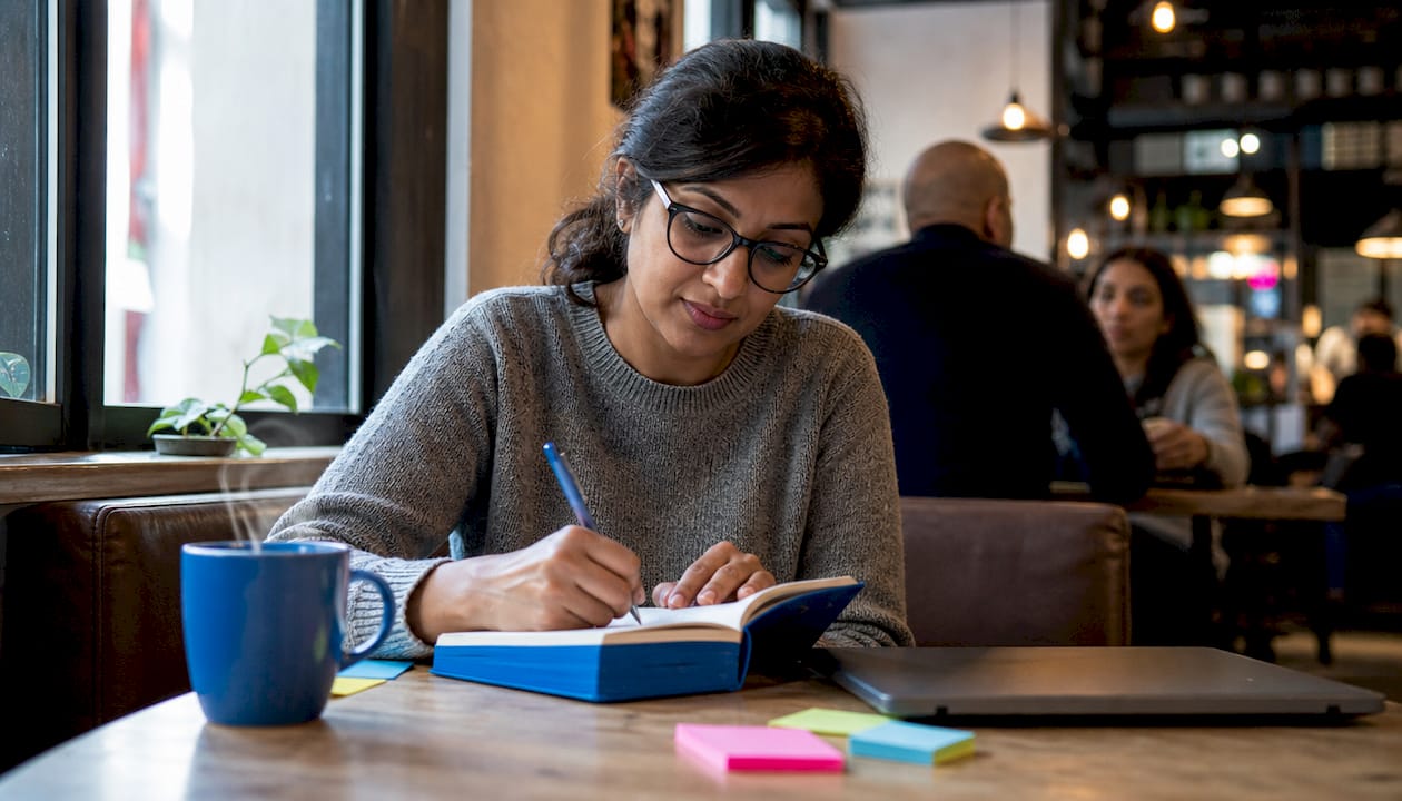 Woman writing user stories at home desk
