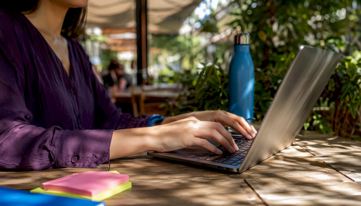 Hands typing on laptop in co-working space