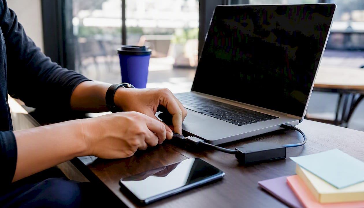 Hands connecting smartphone to laptop for Firebase setup
