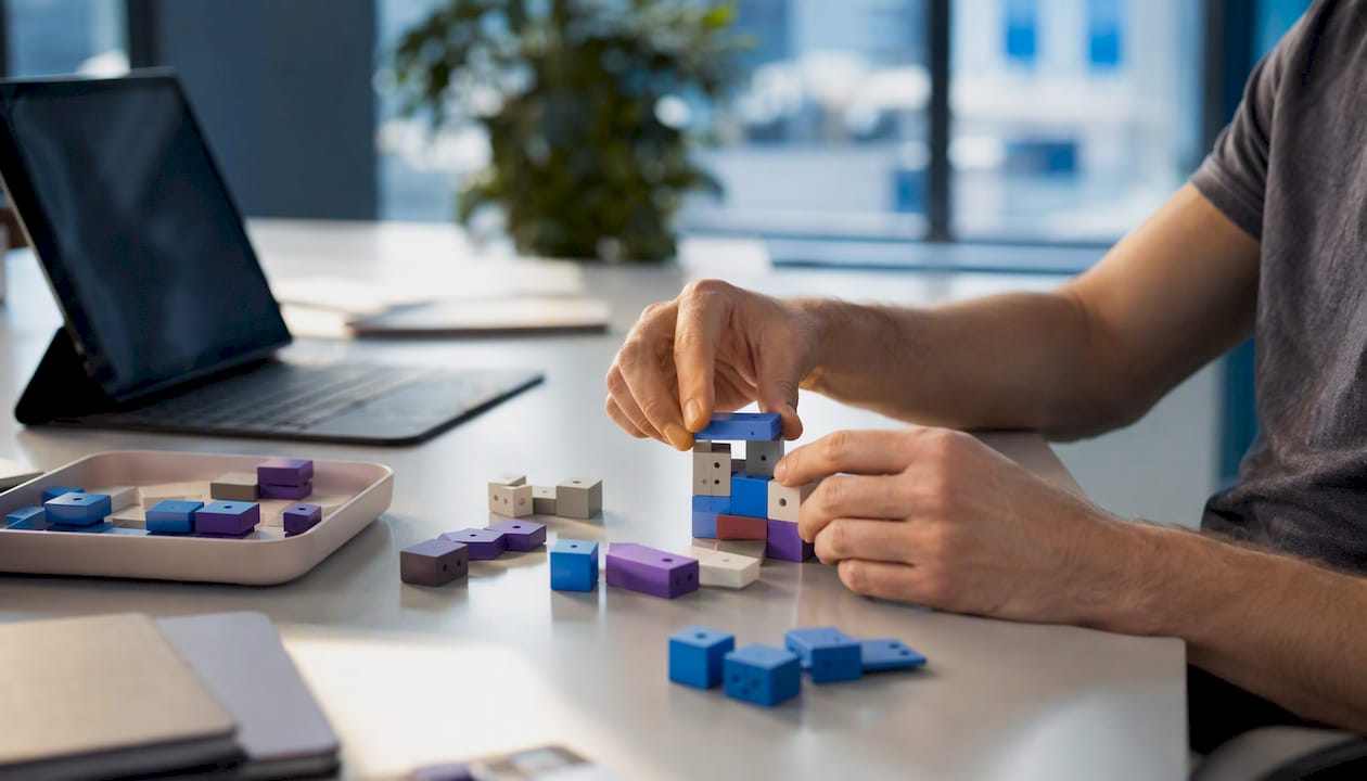 Hands connecting modular tech components on desk