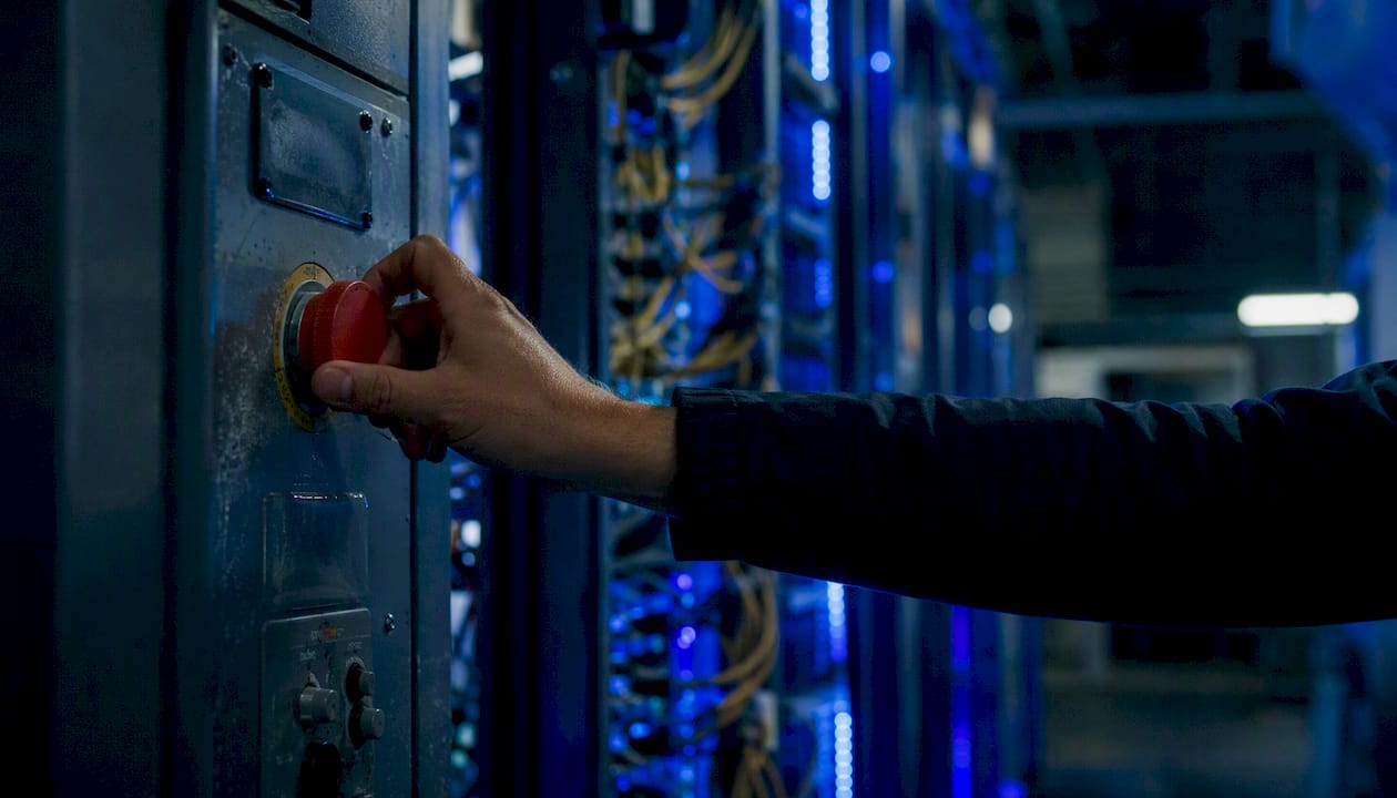 Hand pressing emergency kill switch in server room