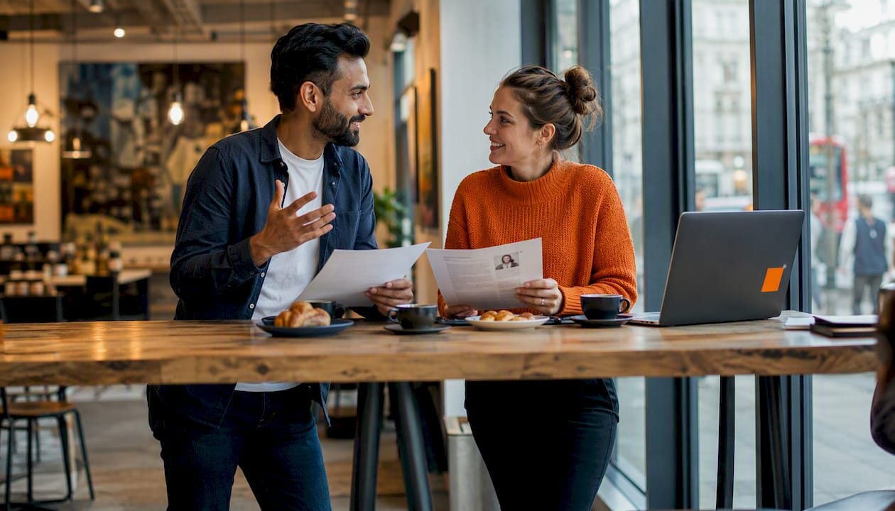 Two colleagues discussing work in UK office environment