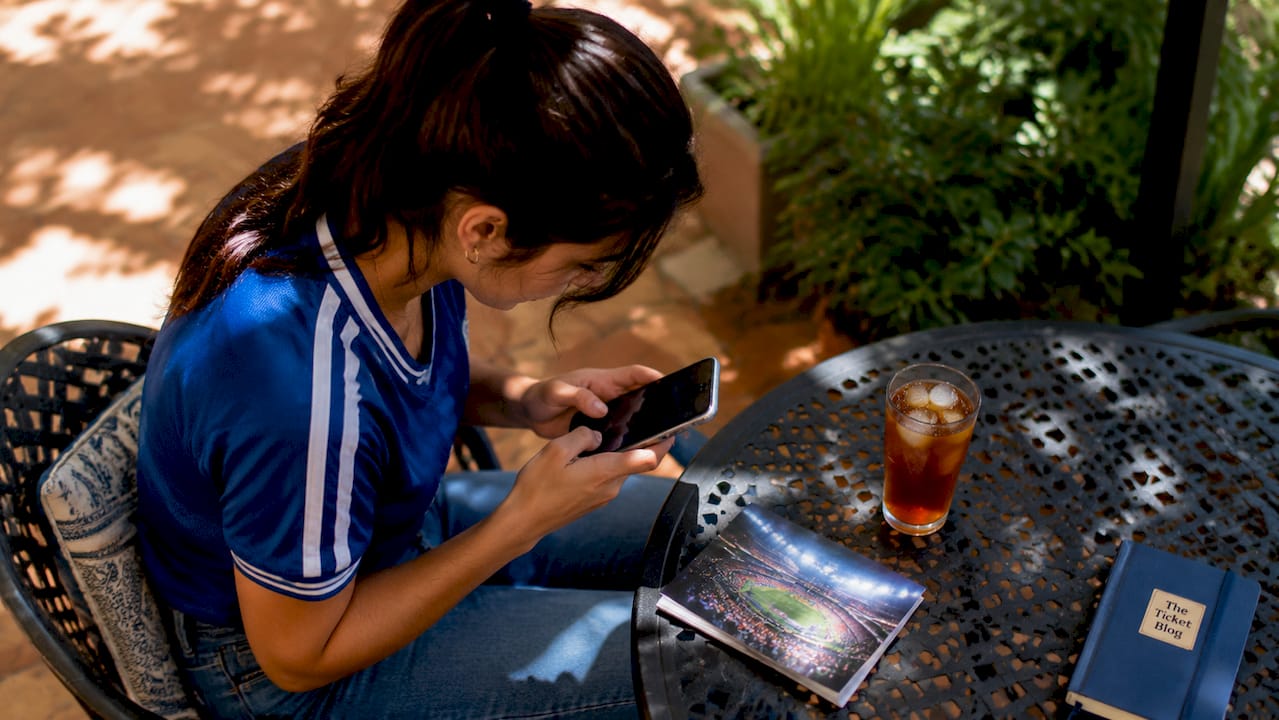 Female sports fan researching ticket discounts on smartphone