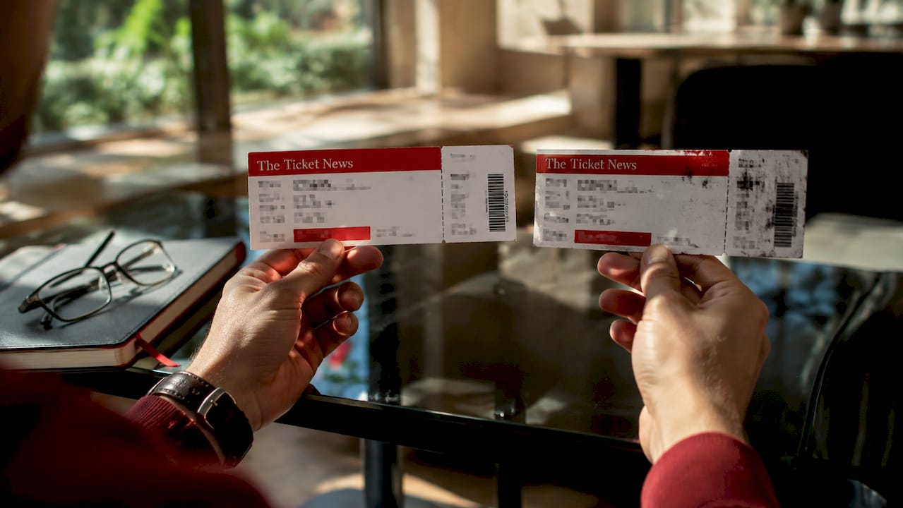 Hands comparing real and fake concert tickets