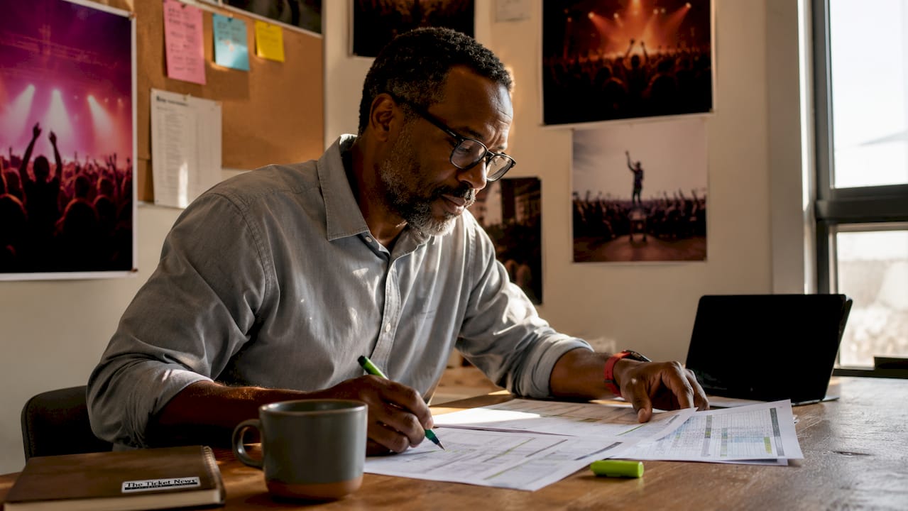 Concert promoter reviewing ticket tier documents at desk