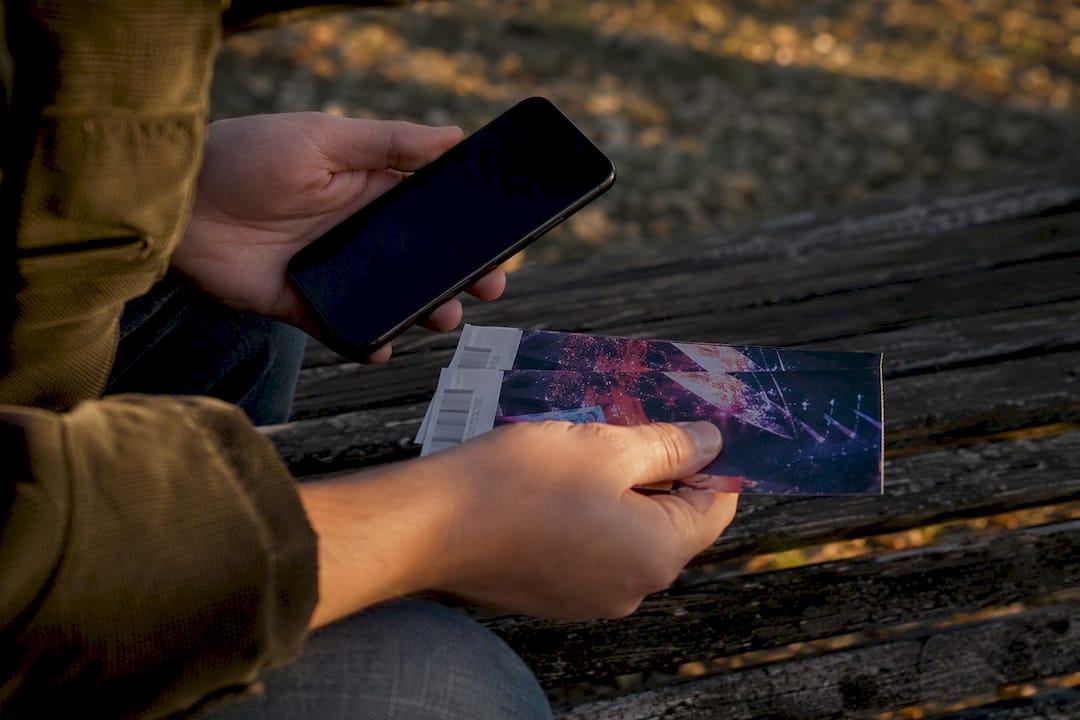 Hands linking phone and tickets symbolizing account connection