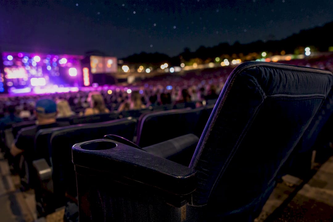 Padded amphitheater seat with cup holder