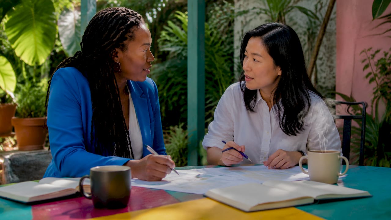 Two colleagues discussing work at coworking cafe