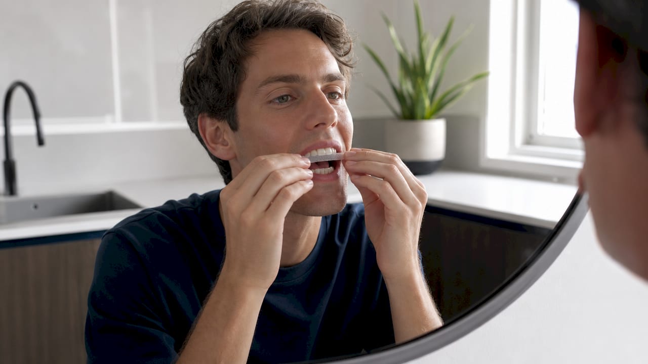 Hands applying teeth whitening strips close-up