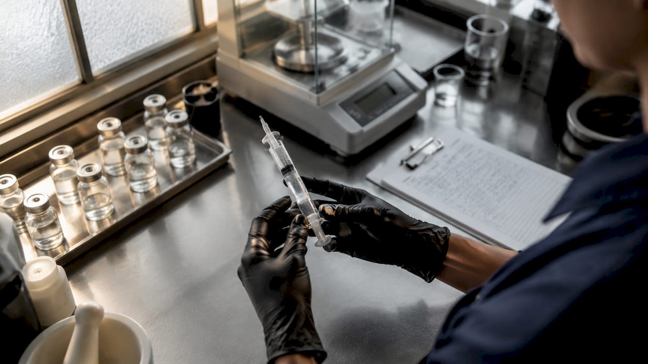 Hands holding peroxide gel syringe in a dental lab