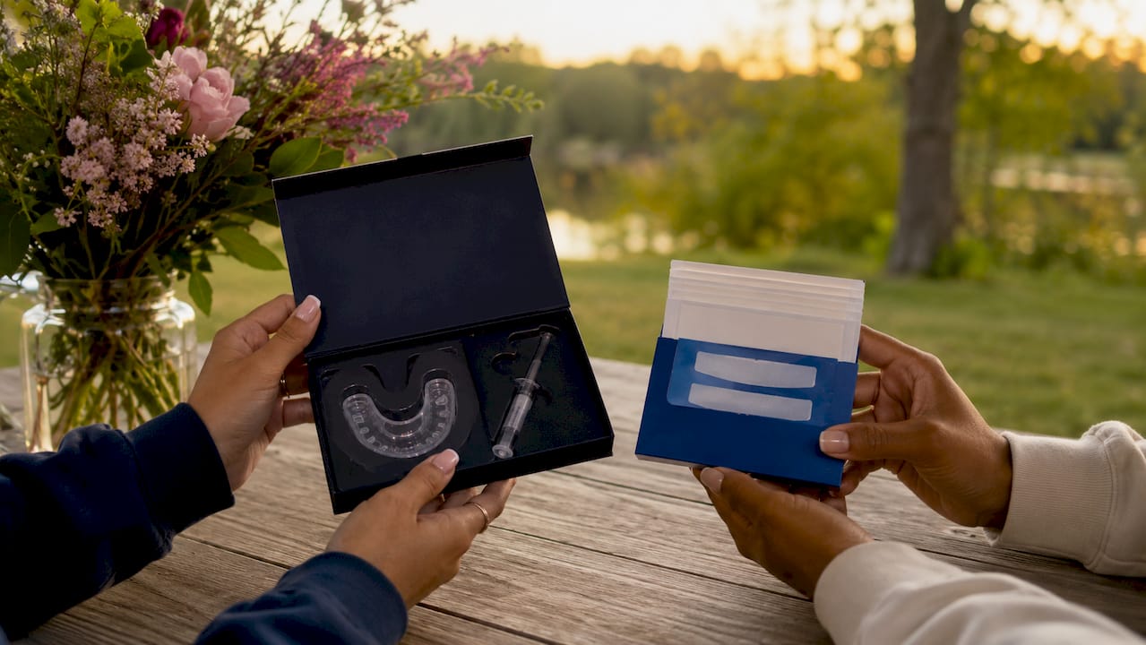 Hands holding professional and OTC teeth whitening kits