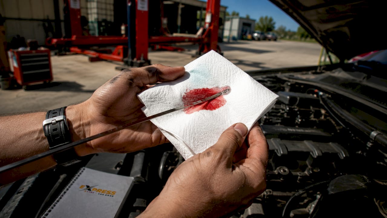 Hands wiping transmission fluid on paper towel