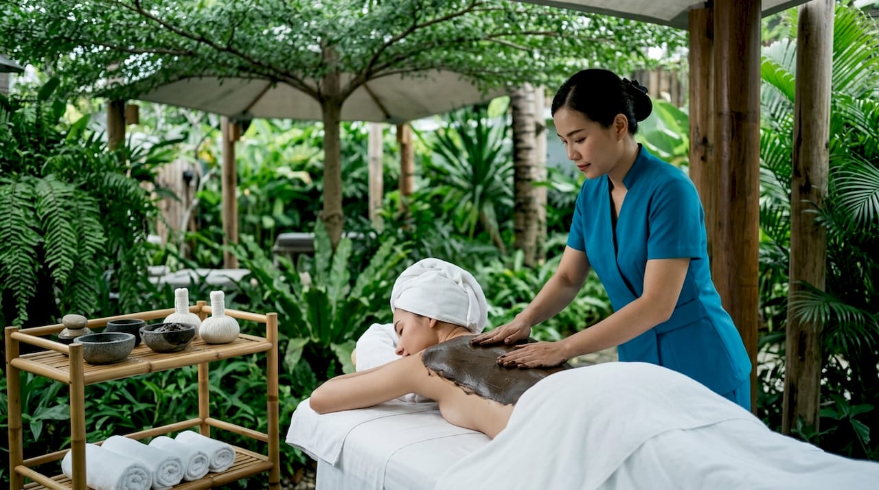 Spa therapist applying mud wrap treatment