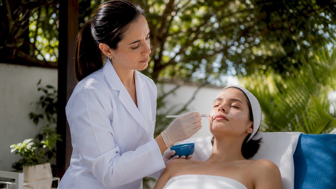 Esthetician applying acne treatment in spa room