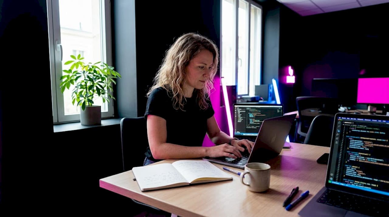 Un développeur web en pleine phase de tests sur son site statique, installé confortablement à la table de la cuisine.