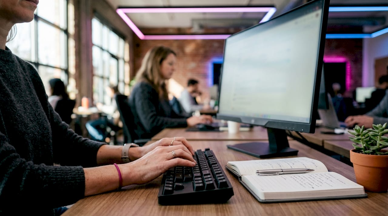 Des mains de femme s’activent sur le clavier d’un ordinateur, au bureau.