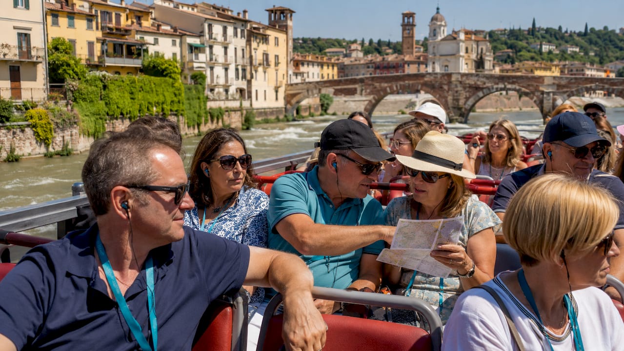 Un gruppo di turisti scende dal bus turistico parcheggiato a Piazza Bra, pronti a scoprire le bellezze di Verona.