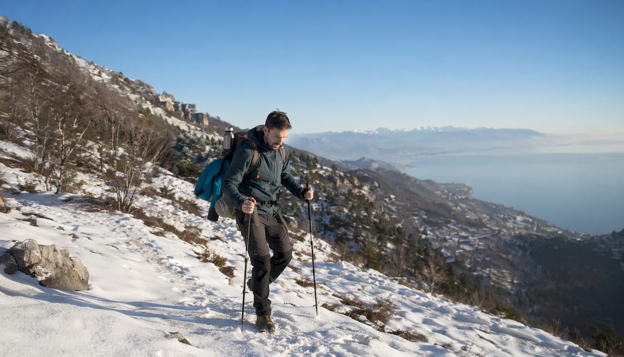 Appassionato di trekking che affronta un sentiero di montagna innevato