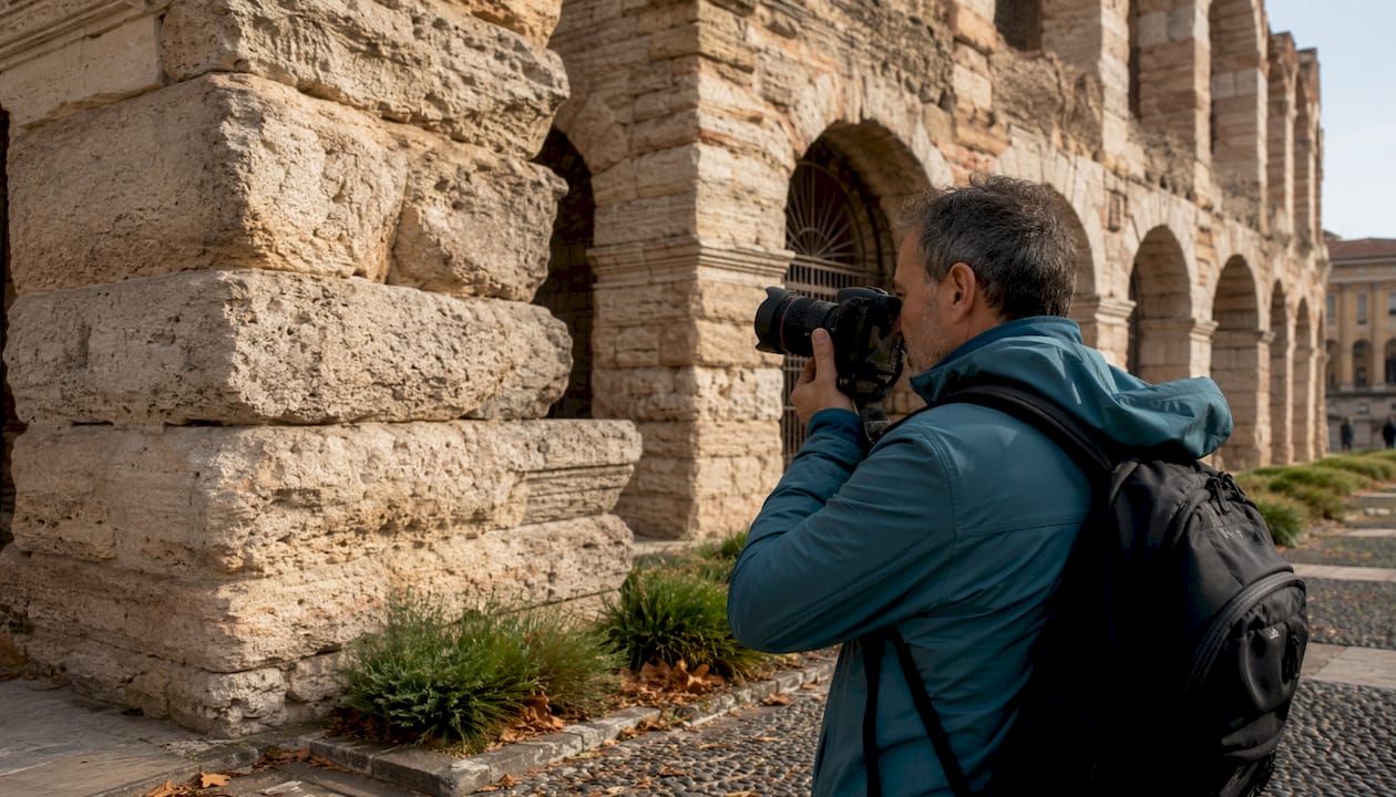 Dettaglio ravvicinato degli archi in pietra dell’Arena di Verona con un uomo che li fotografa