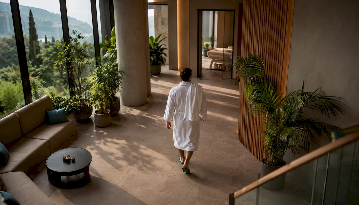Un uomo in accappatoio si aggira tra i corridoi di un hotel con spa, immerso nell’atmosfera rilassante del luogo.