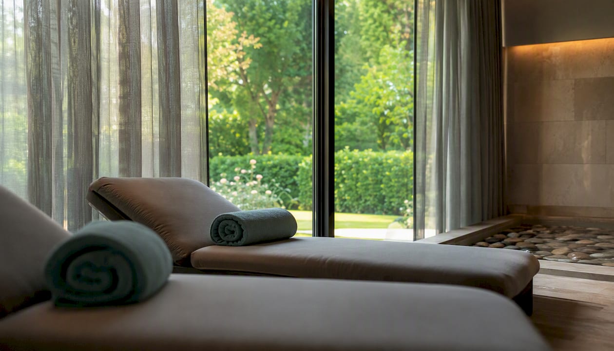 Zona relax della spa dell'hotel, con comode chaise longue immerse nel verde.