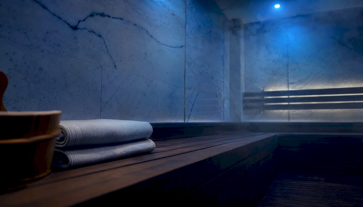 Ambiente accogliente di una sauna in legno, con mestolo e pietre riscaldate pronti per il vapore.