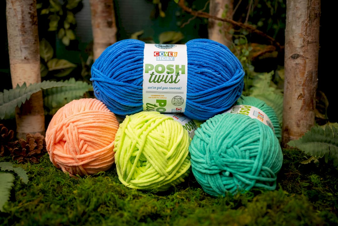 Flat lay of various novelty yarn skeins and knitting tools