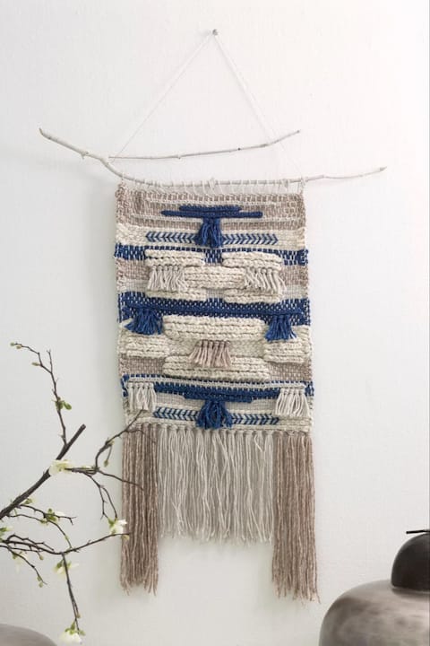 Hands weaving colorful yarn on canvas