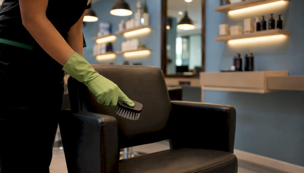 Unas manos protegidas con guantes limpian la tapicería utilizando tiras reactivas para comprobar la eficacia de la limpieza.