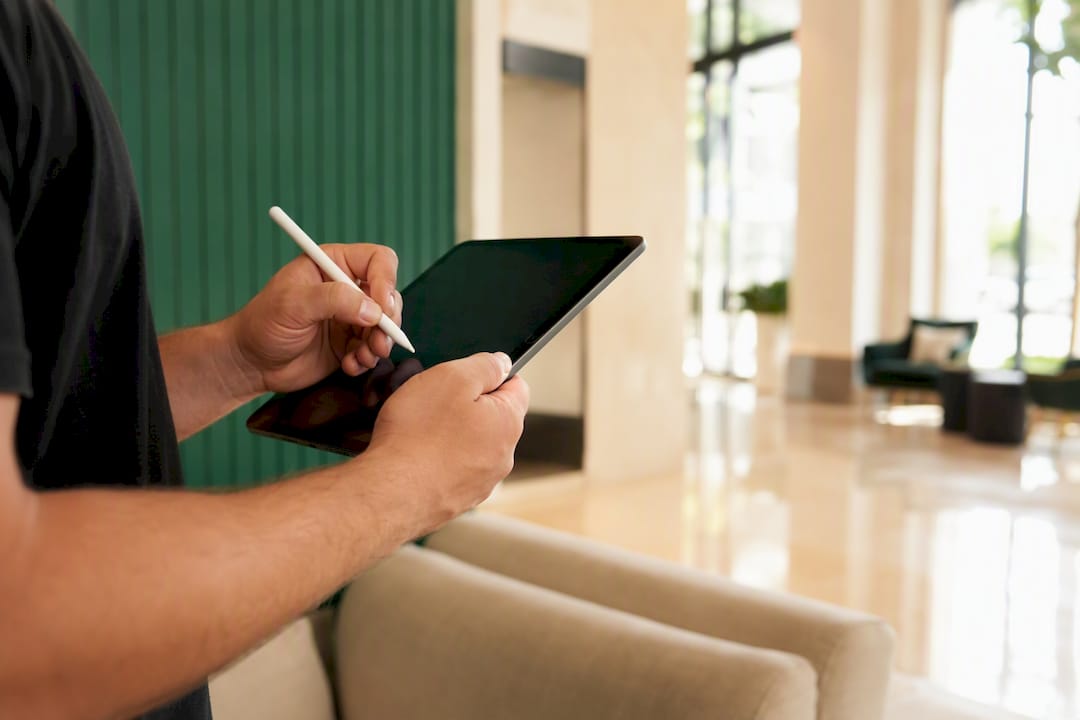 Manos anotando la lista de mantenimiento en la pantalla oscura de una tablet