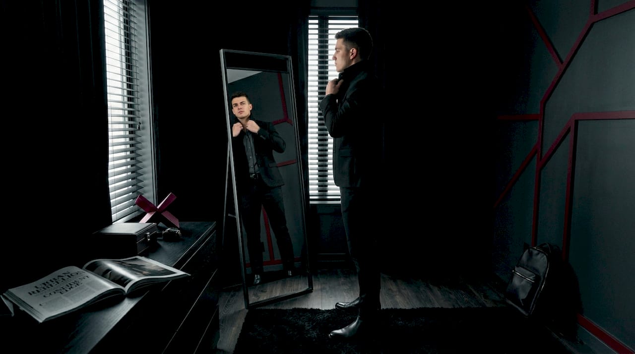 Person adjusting jacket in bedroom mirror