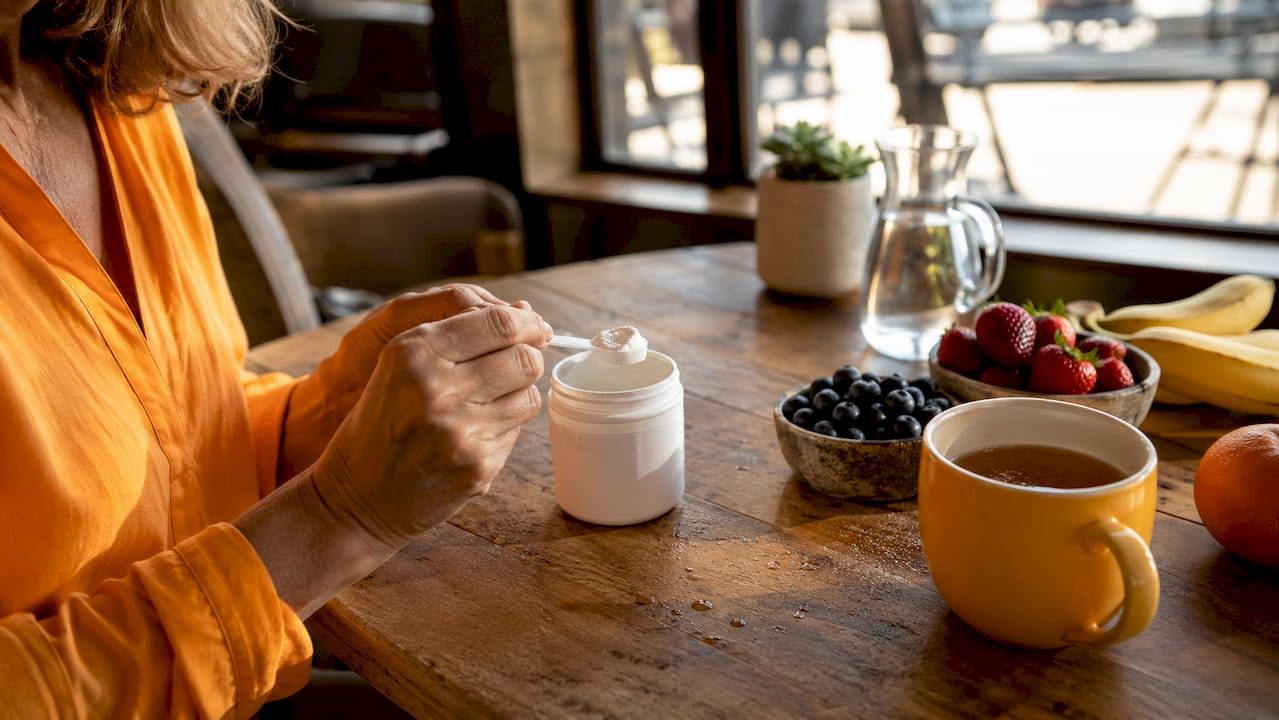 Hands measuring probiotic supplement powder in kitchen