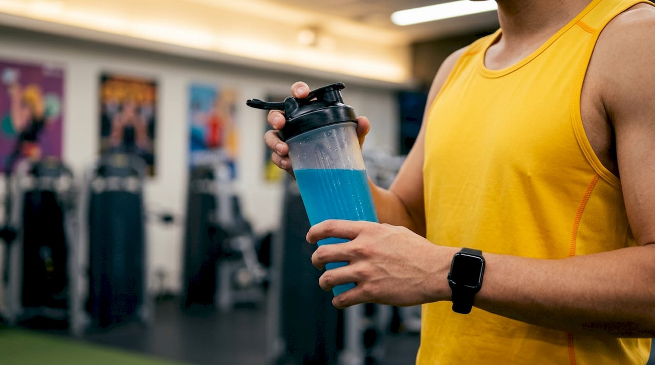 Athlete holding intra-workout drink on running track
