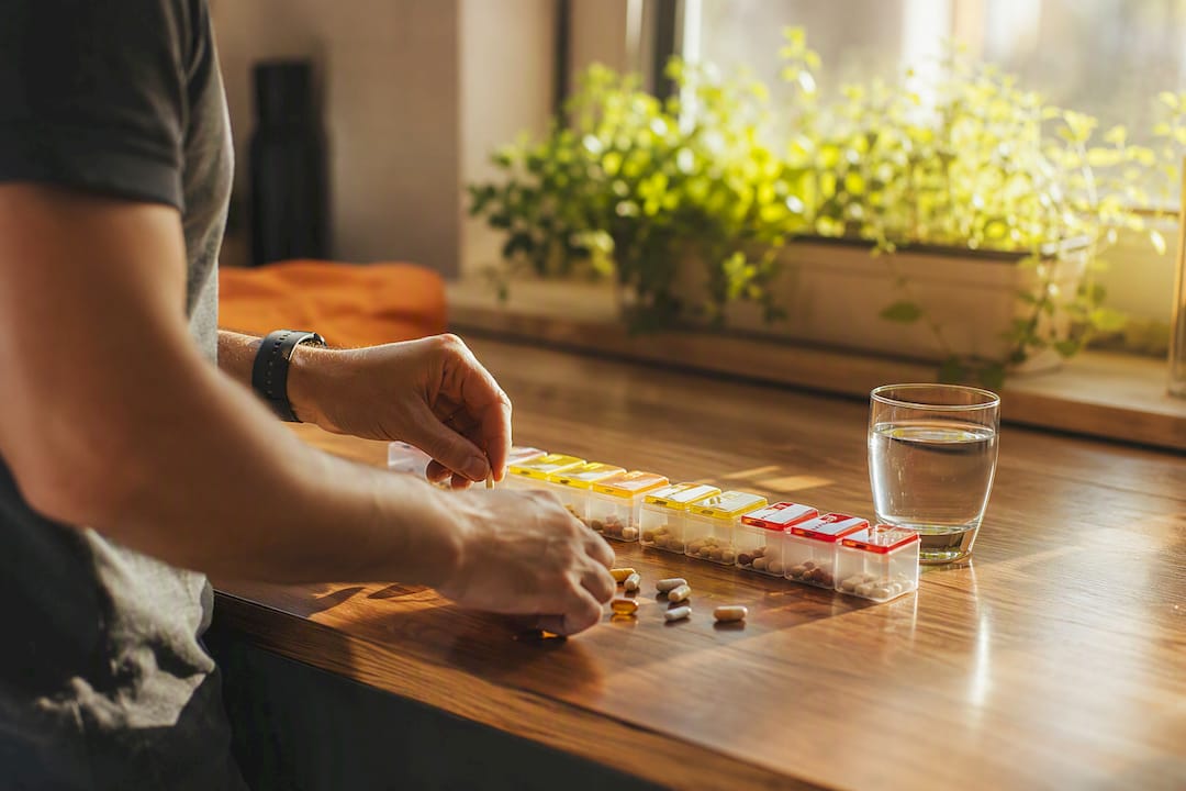 Hands organizing daily supplements with pill organizer