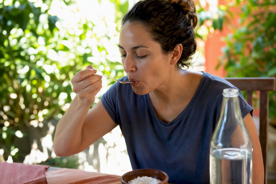 Person sipping small spoonful of electrolyte solution