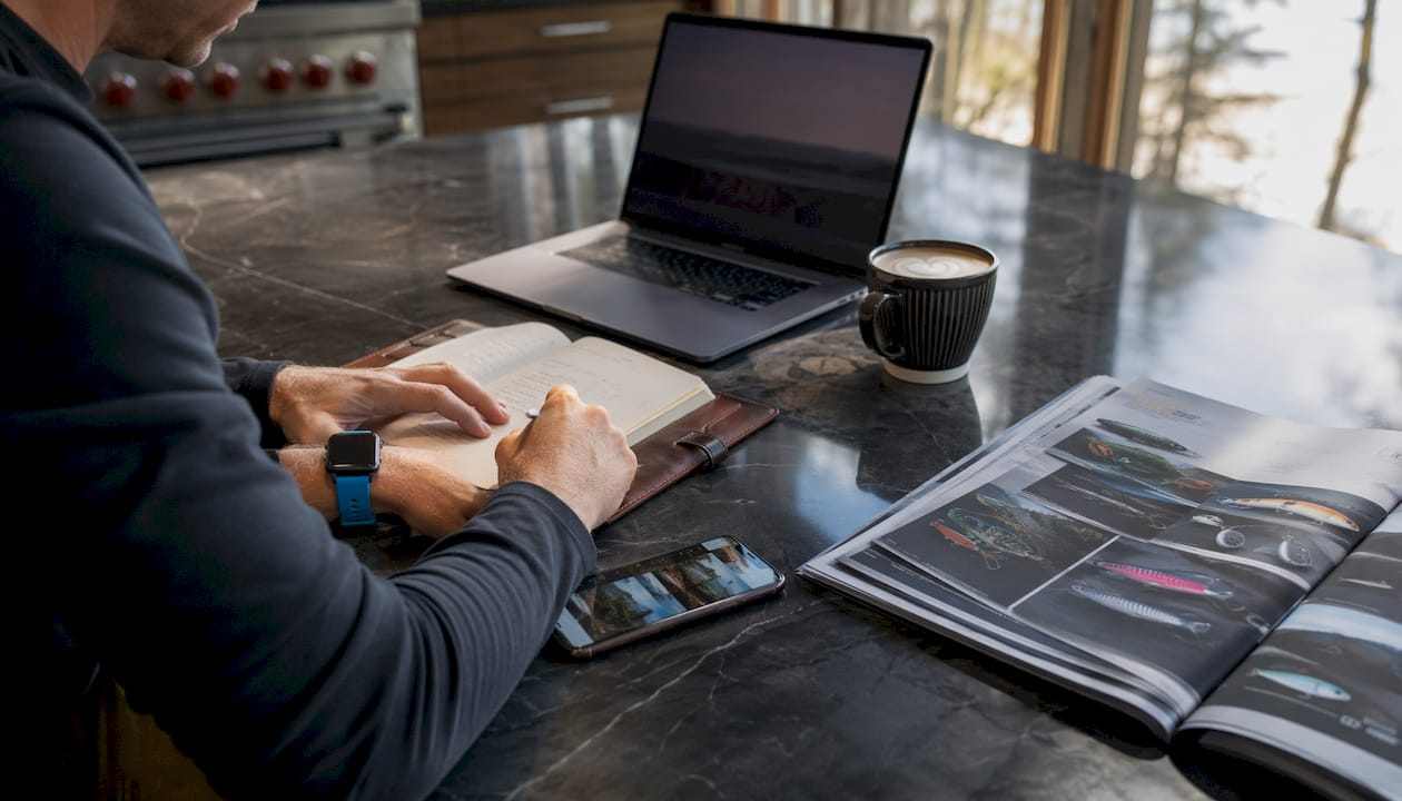 Desk with fishing gear catalog and social media planning