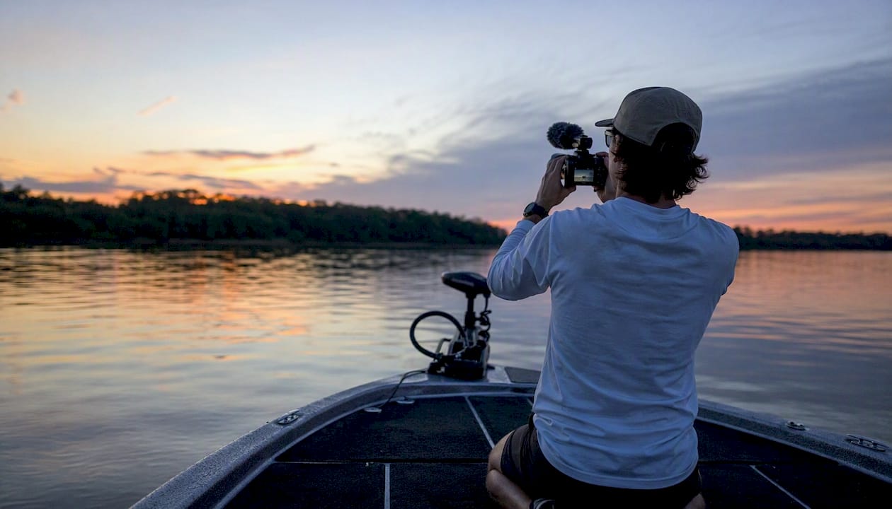 Fishing content creator recording on boat at sunset