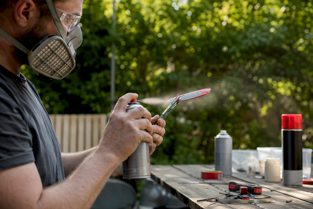 Hands spray painting spinner blade with respirator