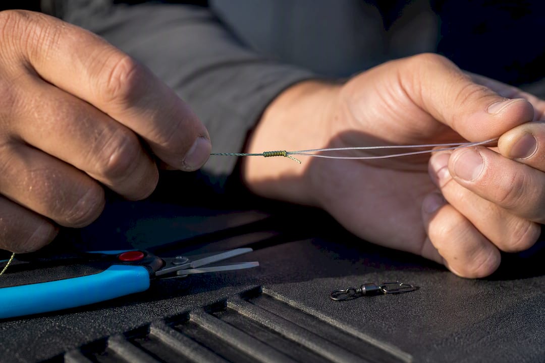 Hands tying an FG knot in leader